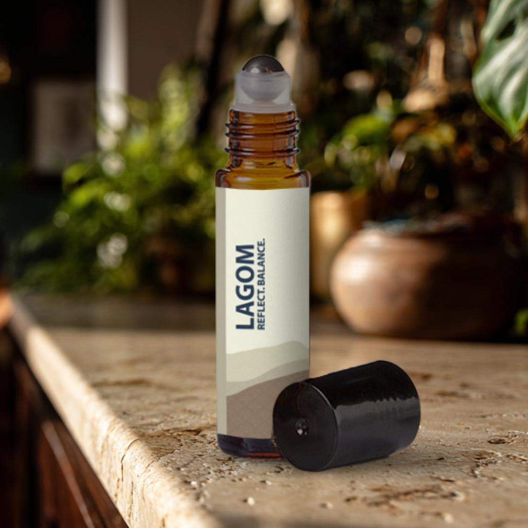 Lagom essential oil roller bottle on a travertine surface with plants in the background.