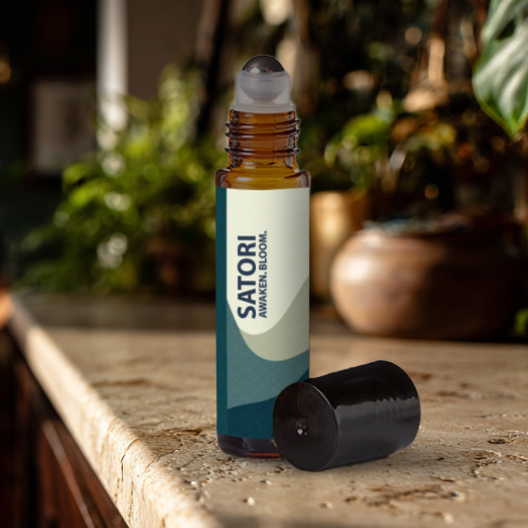 Satori essential oil roller bottle on a travertine surface with plants in the background.